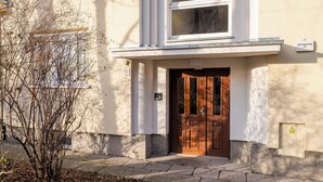 A building entrance with a wooden door, a window above, and a small sign on the wall. - Saska Kępa Lavish Studio (Warszawa)
