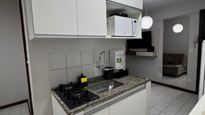 A modern kitchen with white cabinets, a granite countertop, a built-in microwave, and a gas stove. - Apartment in Brasilia, near Plano Piloto, furnished and in a great location. (Plano Piloto)