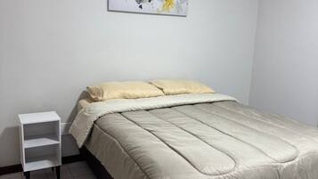 Ein Schlafzimmer mit einem Bett, einem Nachttisch und einem an der Wand hängenden abstrakten Gemälde.