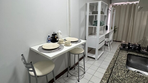 A compact kitchen with a dining area, white cabinetry, a granite countertop, and a tiled floor. - Apartment in Brasilia, near Plano Piloto, furnished and in a great location. (Plano Piloto)