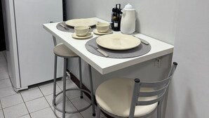 A small kitchenette with a white refrigerator, a white table with a placemat, and a coffee maker. - Apartment in Brasilia, near Plano Piloto, furnished and in a great location. (Plano Piloto)