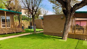 A well-maintained grassy area with wooden structures, possibly a hotel or resort. - Mobile home with air conditioning, terrace and pool (Padenghe sul Garda)