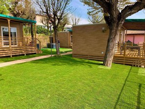 A well-maintained grassy area with wooden structures, possibly a hotel or resort. - Mobile home with air conditioning, terrace and pool (Padenghe sul Garda)