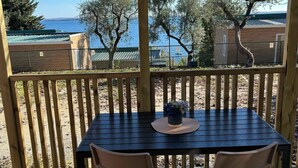 Una terraza de madera con una mesa y sillas, con vistas a un cuerpo de agua y árboles.