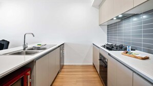 Una cocina moderna con un lavamanos de acero inoxidable, una estufa a gas y un lavavajillas.
