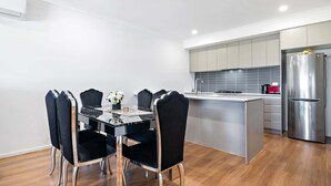 Una cocina moderna con una isla central, electrodomésticos de acero inoxidable y sillas negras con patas metálicas.
