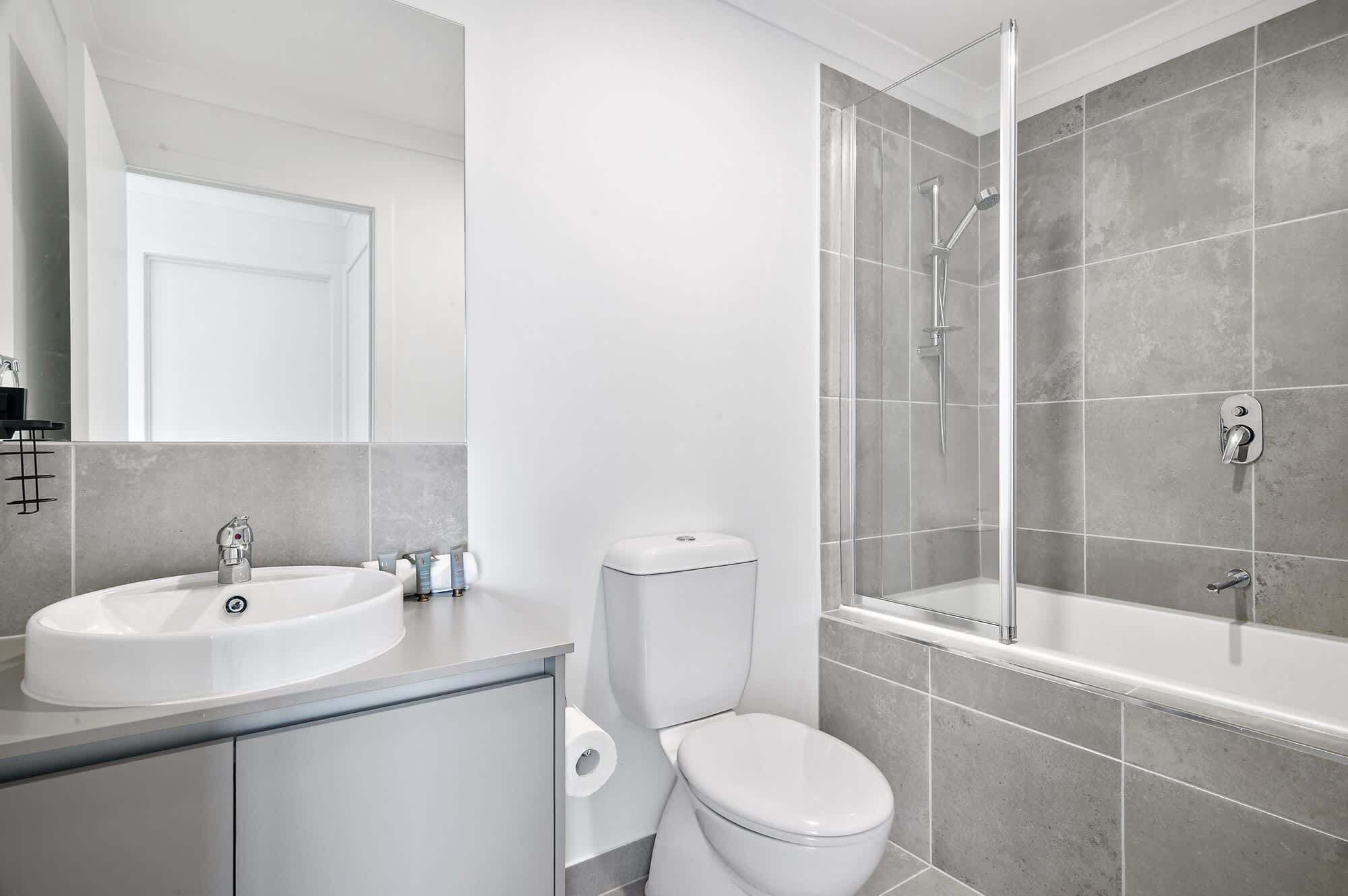 Un bagno moderno con lavandino, WC e cabina doccia in vetro.