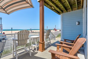 Eine Terrasse am Strand mit Adirondack-Stühlen, einem kleinen Tisch und Blick aufs Meer.