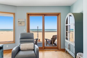 Ein Zimmer mit Blick auf den Strand, ein Sessel, ein Tisch und ein Schrank.