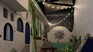 An interior courtyard with potted plants, a wooden bench, and a staircase leading to an upper level. - Sayu Life (Sayulita)