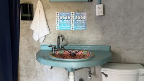 A bathroom with a blue sink, a white toilet, a towel hanging on the wall, and a mirror above the sink. - Sayu Life (Sayulita)