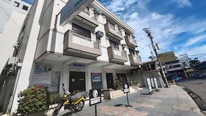 Un hotel Midori con fachada moderna, un sistema de reservas visible y una motocicleta estacionada en la entrada.