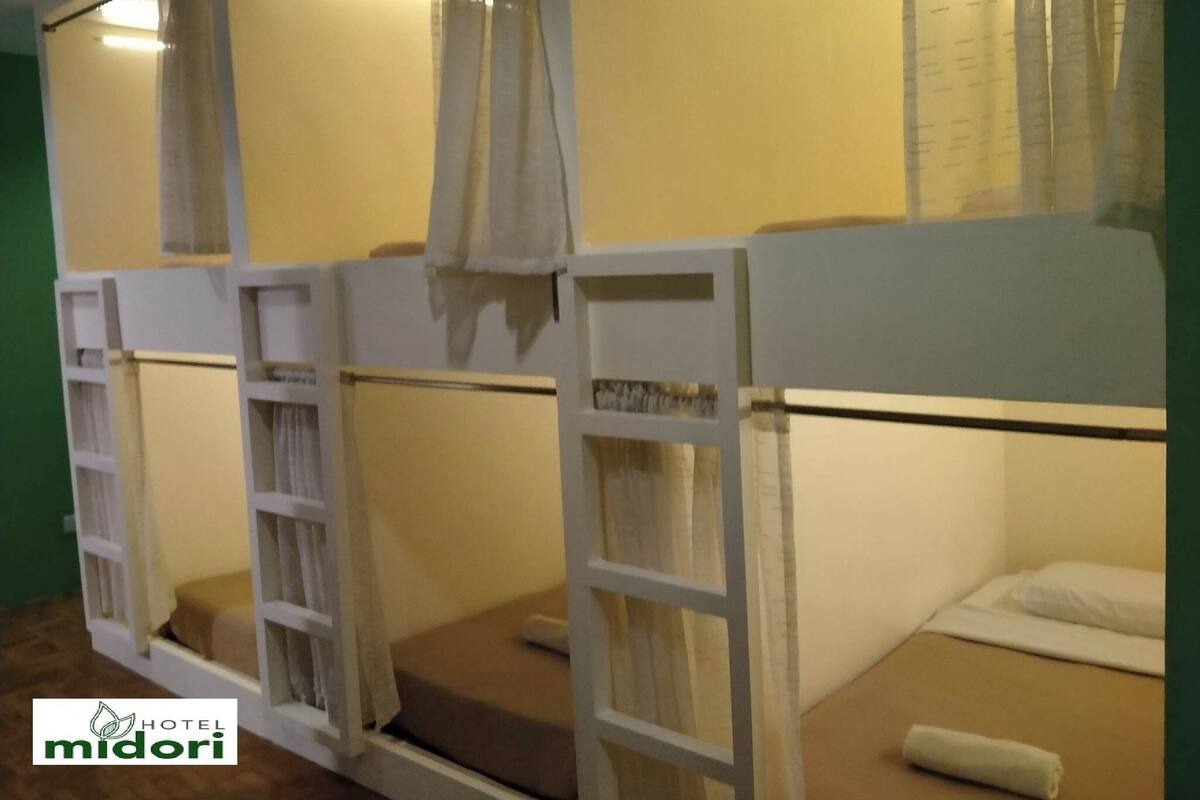 Une chambre avec des lits superposés, chacun étant équipé d’une échelle et d’une petite table de chevet.