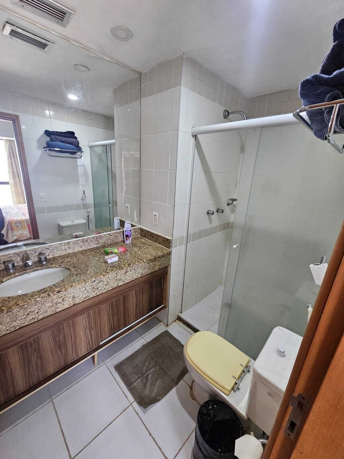 A bathroom with a granite countertop, a sink, a toilet, and a glass shower enclosure.