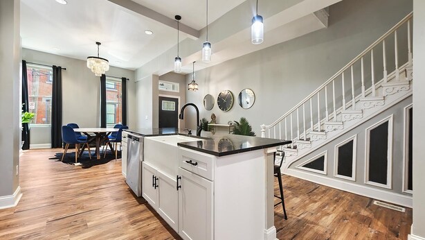 Una cocina moderna con una isla central, armarios blancos e iluminación colgante.