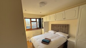 A bedroom with a large bed, white bedding, a radiator, a window with a view of buildings, and white cabinetry. - House in Tamebridge, Walsall

Near train and bus routes to Birmingham (Walsall)