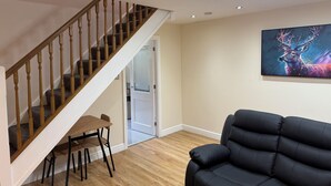 A staircase with wooden balusters and carpeted steps, a black leather sofa, and a painting on the wall. - House in Tamebridge, Walsall

Near train and bus routes to Birmingham (Walsall)