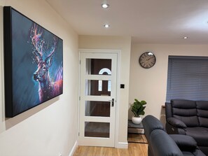 A modern living room with a large abstract painting, a black leather sofa, a wooden floor, a white door, and a wall clock. - House in Tamebridge, Walsall
Near train and bus routes to Birmingham (Walsall)