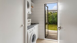 Une buanderie équipée d’un lave-linge, d’un sèche-linge et d’étagères où sont rangés les produits de lessive.