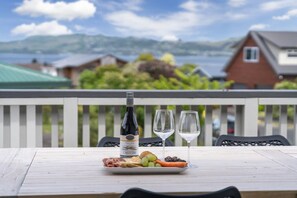 Ein Tisch mit einer Weinflasche, zwei Gläsern und einem Teller Essen auf einem Balkon mit Blick auf eine schöne Landschaft.