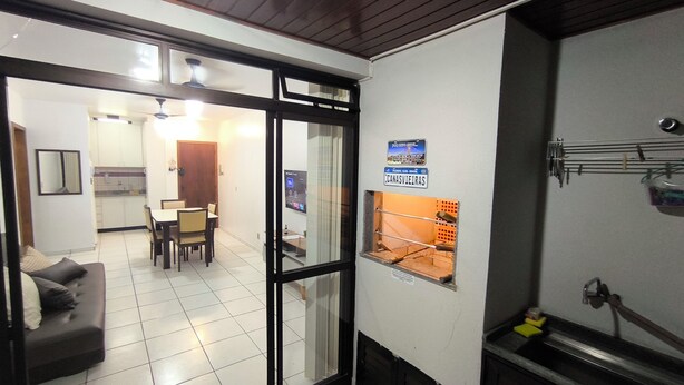 Un salon avec un canapé, un coin repas avec une table et des chaises, et une cuisine visible à travers une porte ouverte.