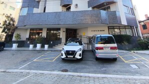 Un hôtel à plusieurs étages, doté d’un design moderne, avec des balcons à chaque niveau et un espace de stationnement à l’avant.