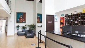 A reception area with a counter, seating, and artwork on the walls. - Apartamentos La Frontera (Medellín)