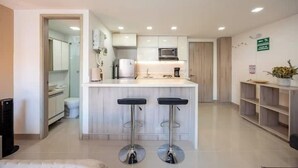 A modern kitchen with a central island and two bar stools. - Apartamentos La Frontera (Medellín)
