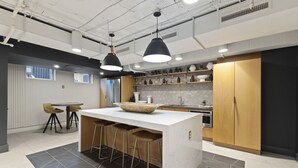Una cocina moderna con una isla central, taburetes de bar, iluminación colgante y vistas a la ciudad.