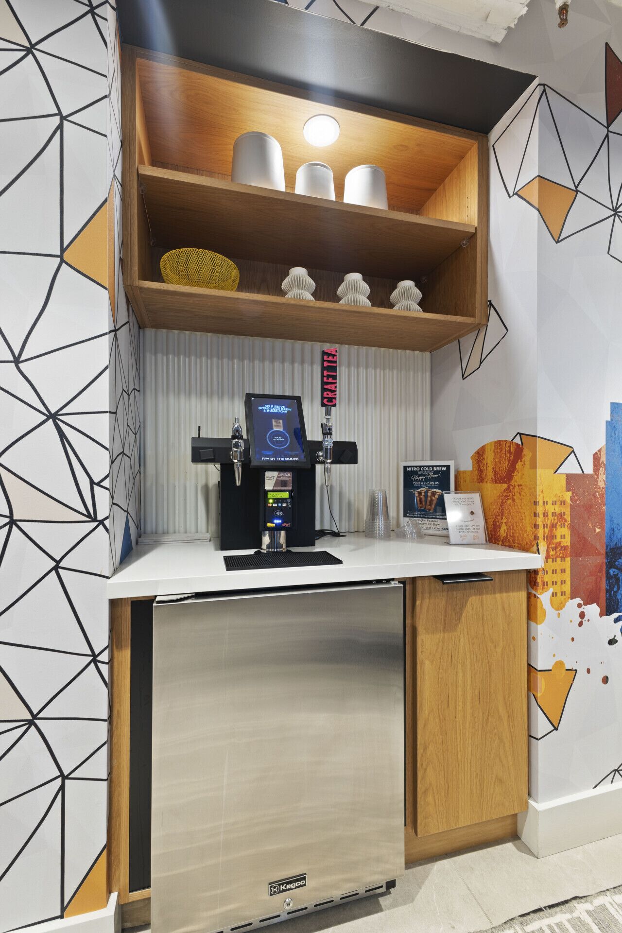 Una estación de café con un terminal de pago digital, un letrero de té artesanal y un letrero de cold brew Niro.