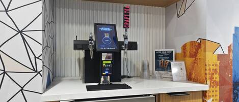 Una estación de café con un terminal de pago digital, un letrero de té artesanal y un letrero de cold brew Niro.