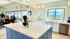 A spacious kitchen with a large island, white cabinetry, and a view of the outdoors. - Stunning Private Beachfront Villa- Private Pool, Sandy Beach, Roof Deck Fire Pit (Cabo San Lucas)