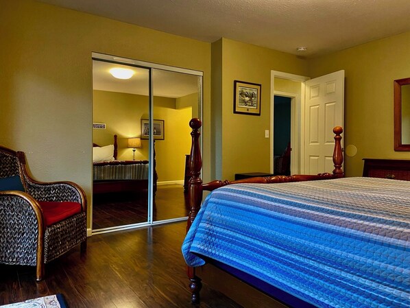 A bedroom with a bed, a chair, a door, and a mirror. - Modern McKinleyville 3BR Retreat | Deck, Gazebo, Fire pit & Lawn Games (Mckinleyville)