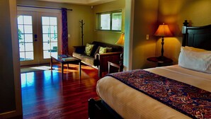 A hotel room with a bed, a desk, a chair, a lamp, and a view through a door. - Ocean-view studio near redwoods and beaches—your basecamp for Trinidad adventure. (Trinidad)