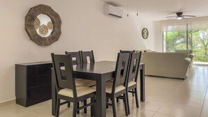 Ein Essbereich mit Tisch und Stühlen, einer Couch, einem Deckenventilator und einer Klimaanlage.