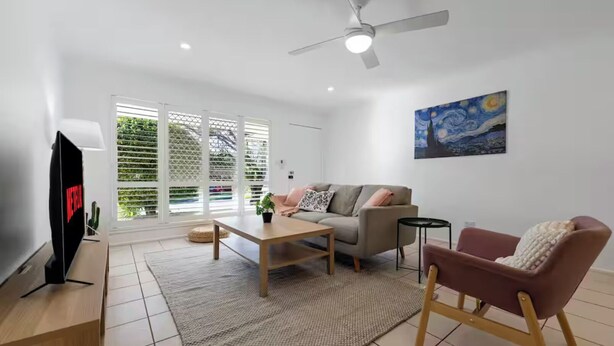 Un salon moderne avec un canapé, une table basse, un téléviseur et un ventilateur de plafond.