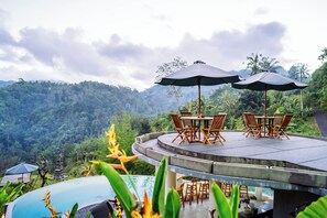 A terrace with a table and chairs, surrounded by lush greenery and a mountainous backdrop. - Ngetis Sidemen Villa & Retreat (Sidemen)