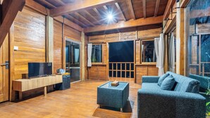L'intérieur d'un chalet en bois, avec un téléviseur, un canapé et une table basse.