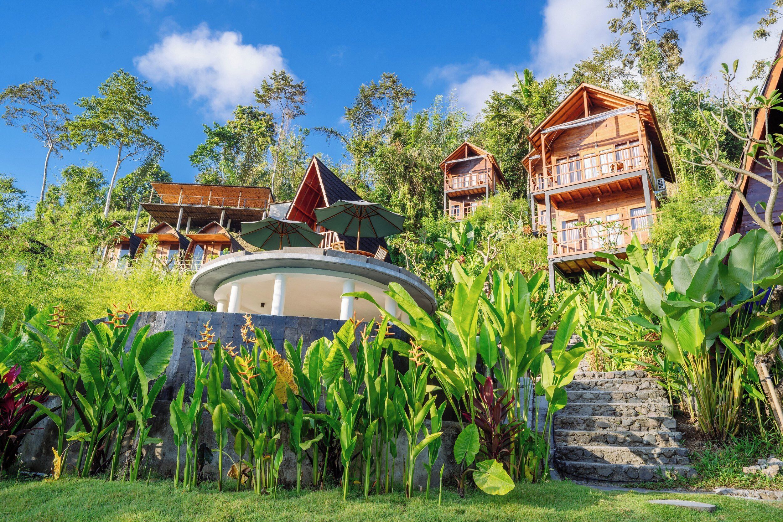 A resort with multiple wooden cabins, a central circular structure, and lush greenery.