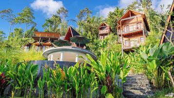 A resort with multiple wooden cabins, a central circular structure, and lush greenery.
