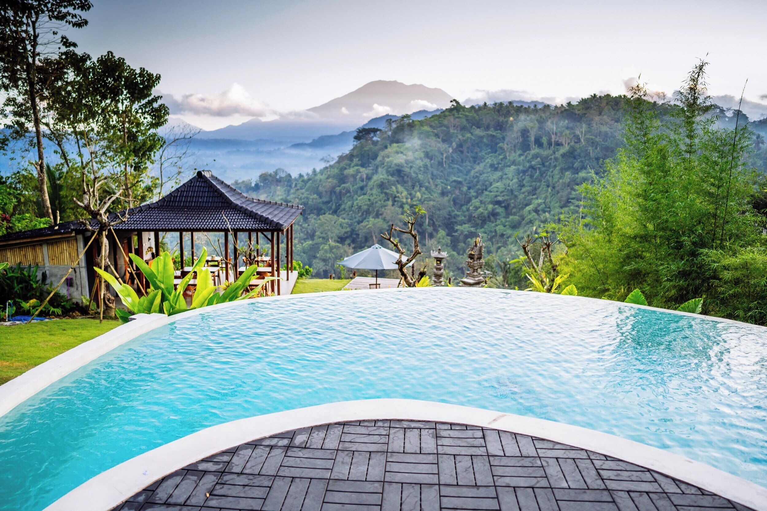 A pool with a view of a mountain range and a gazebo.
