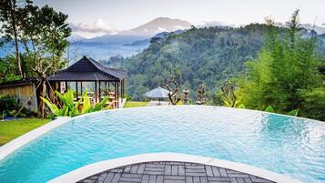 A pool with a view of a mountain range and a gazebo.