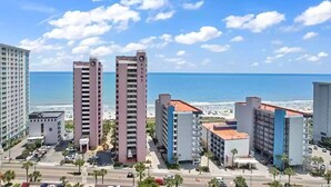 Un paysage urbain côtier avec de hauts immeubles, une plage et un ciel bleu dégagé.
