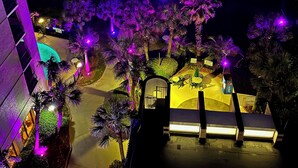 Un hôtel situé en bord de mer, doté d’une piscine, de palmiers et offrant une vue sur l’océan.