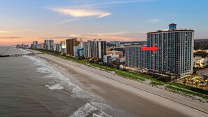 Eine Küstenstadt mit hohen Gebäuden, einem Strand und einem markanten Hotel mit einem Uhrturm.