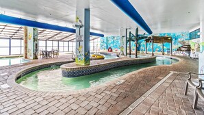 Une piscine intérieure avec un sol carrelé, un jacuzzi et une fresque murale.