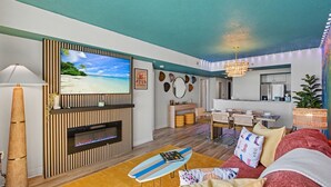 Un salon avec un téléviseur, une cheminée, un coin repas et une cuisine à l’arrière-plan.