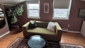 A cozy living room with a green sofa, a round glass coffee table, and a large potted plant. - Ideal Stay for City Explorers (Halifax)