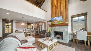 Un salón espacioso con chimenea, una cocina al fondo y un ventanal con vistas.