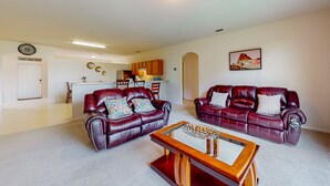 A living room with two leather sofas, a wooden coffee table, and a kitchen in the background. - Palm Bay Cove | House in Palm Bay (Palm Bay)